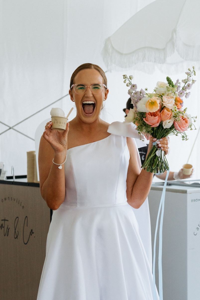 A bride holding a cup of gelato and her bouquet