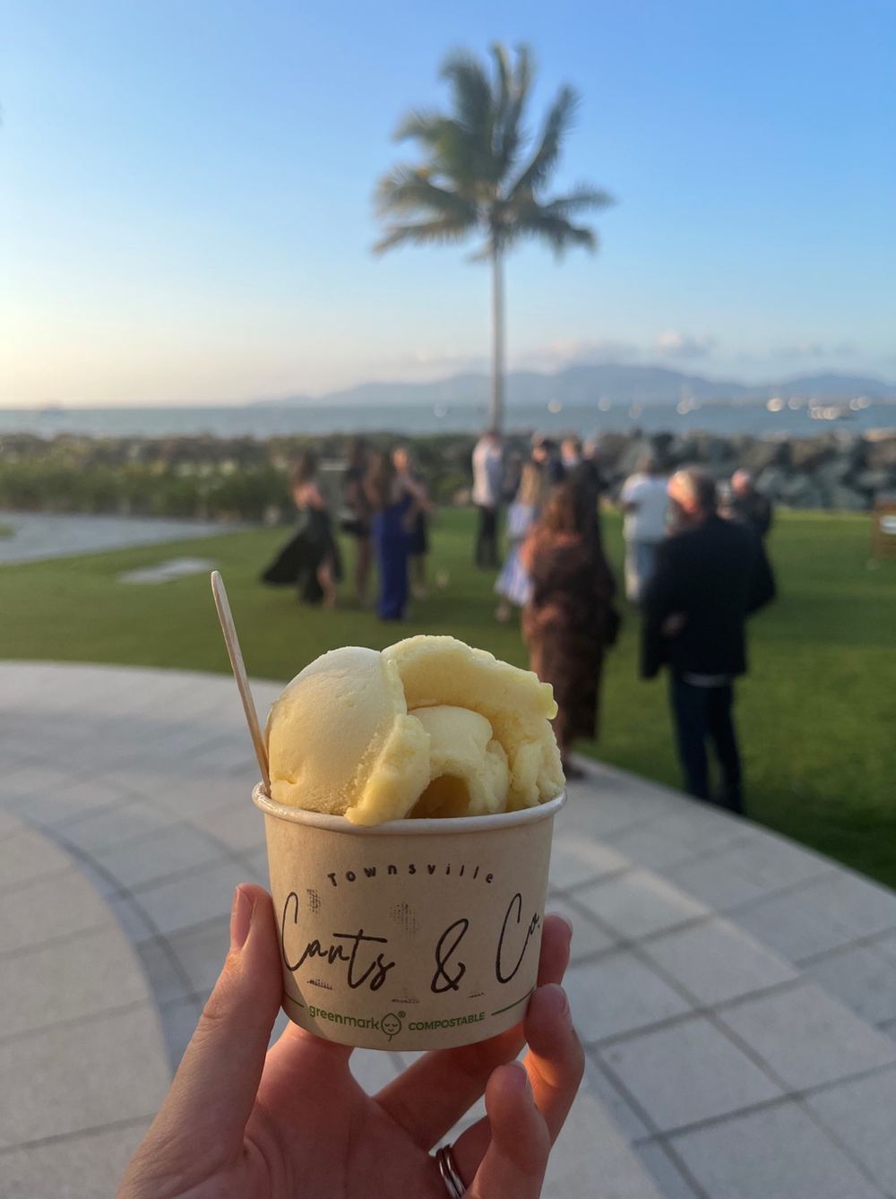 A cup of gelato held up on The Strand at sunset